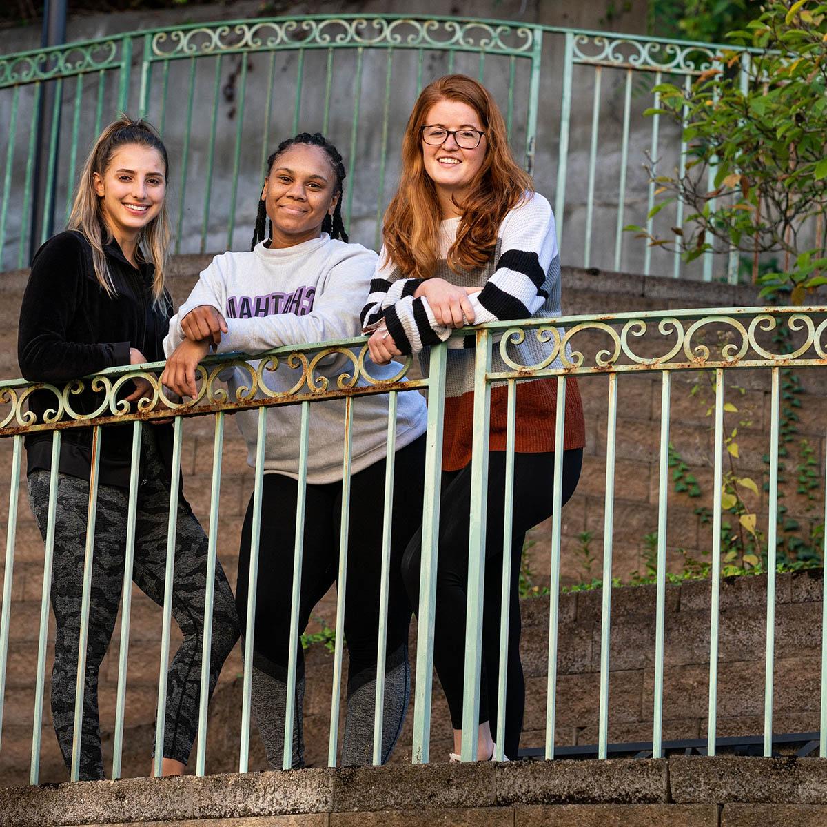 图为三名波胆网站ELOTD学生在大门前摆姿势